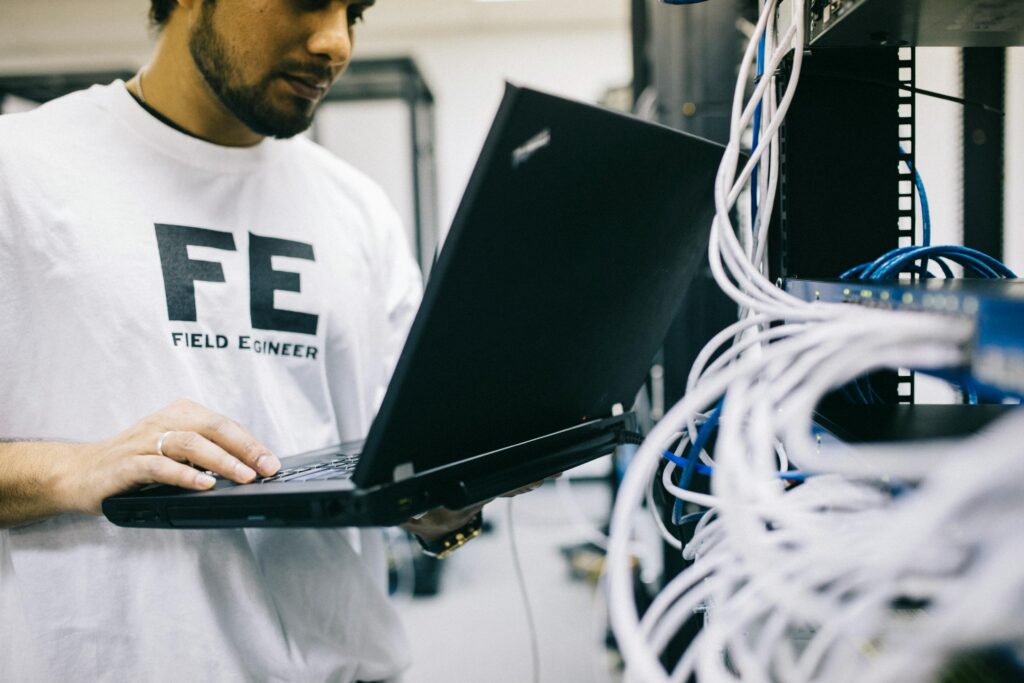 Crop focused Asian engineer in white shirt using modern netbook while working with hardware